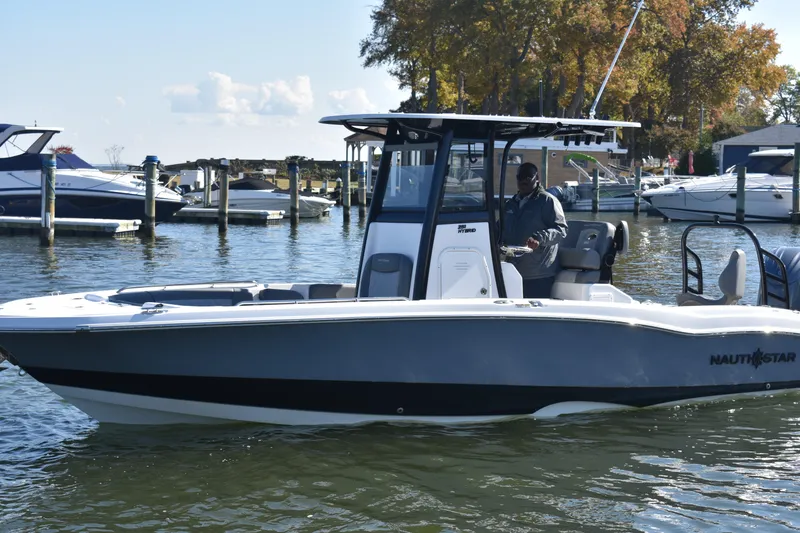 Slide: The Image of 2025 NauticStar 251 Hybrid boat on water, docked with other boats in the background. - 65