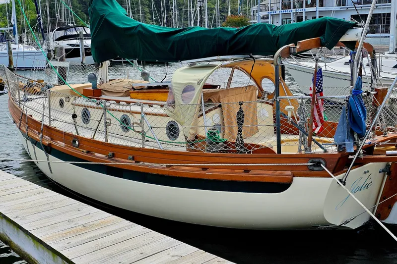 Slide: The Image of 1985 Sam L. Morse Bristol Channel Cutter 28 docked, featuring classic wooden design and green sail cover. - 2