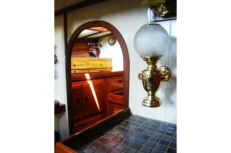 Slide: The Image of Interior of 1985 Sam L. Morse Bristol Channel Cutter 28, featuring wood cabinetry and brass lamp. - 9