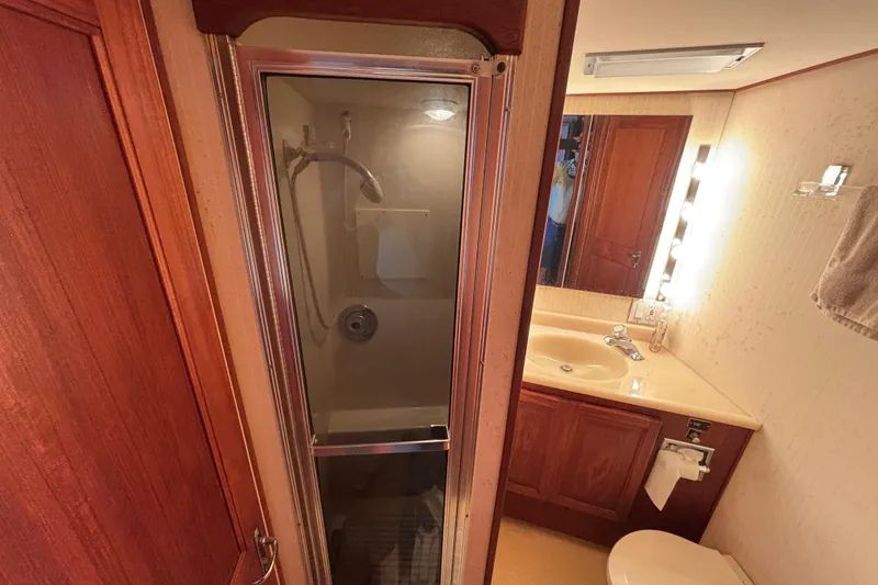 Slide: The Image of Bathroom interior of 1988 Viking Boats 41 Convertible, featuring shower, sink, and wooden cabinetry. - 32