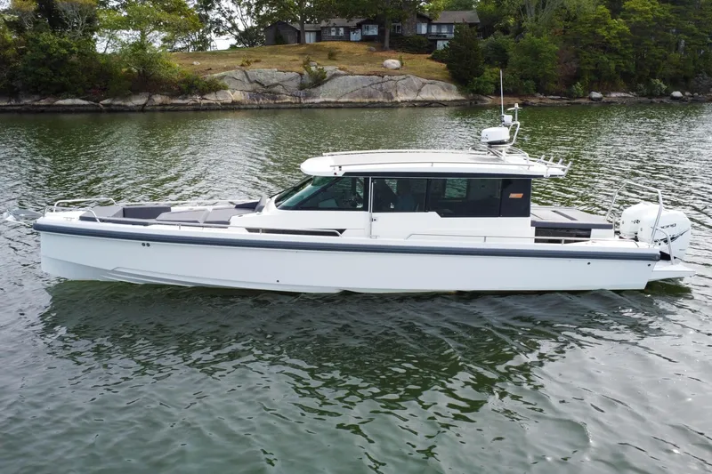 Slide: The Image of 2018 Axopar 37 Sport Cabin R boat on calm water near rocky shoreline. - 1