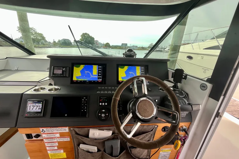 Slide: The Image of 2018 Axopar 37 Sport Cabin R helm with navigation screens and steering wheel. - 11