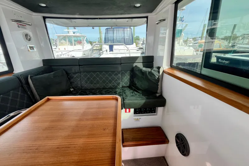 Slide: The Image of Interior of 2018 Axopar 37 Sport Cabin R with cushioned seating and wooden table. - 18