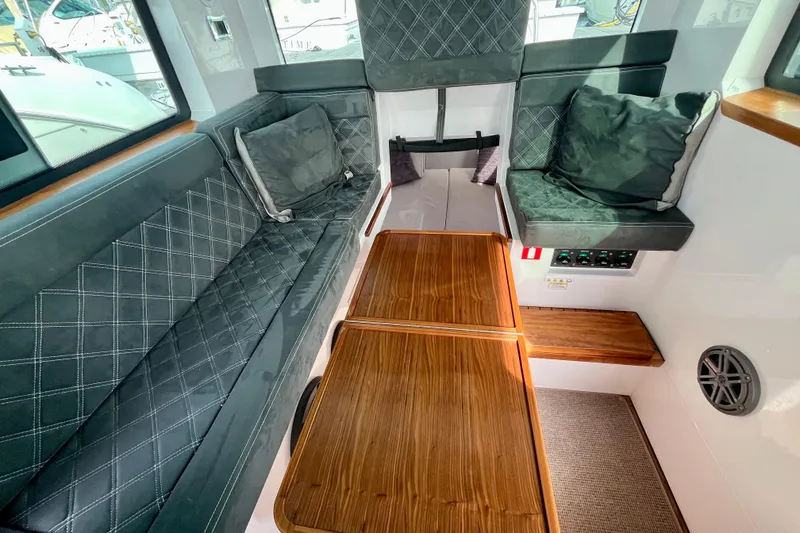 Slide: The Image of Interior of 2018 Axopar 37 Sport Cabin R with cushioned seating and wooden table. - 21