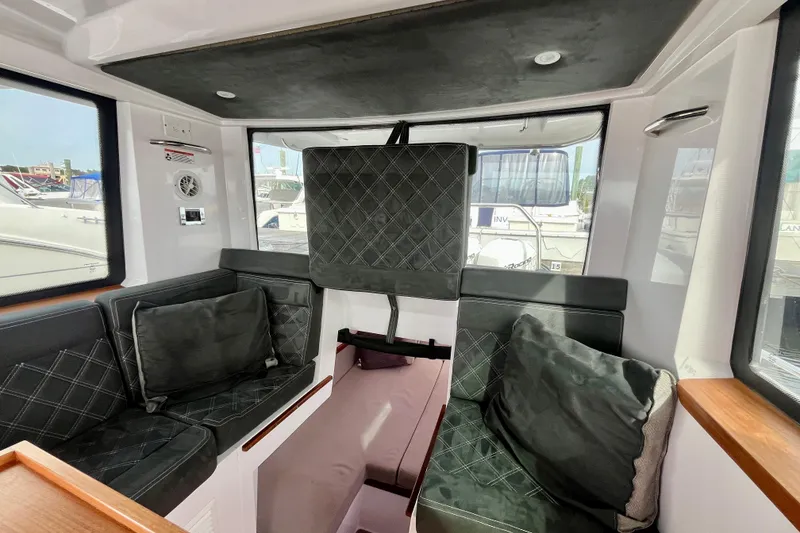 Slide: The Image of 2018 Axopar 37 Sport Cabin R interior with cushioned seating and windows. - 23