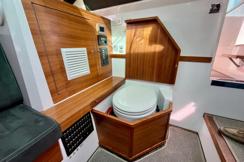 Slide: The Image of 2018 Axopar 37 Sport Cabin R interior with wooden cabinetry and compact marine toilet. - 32