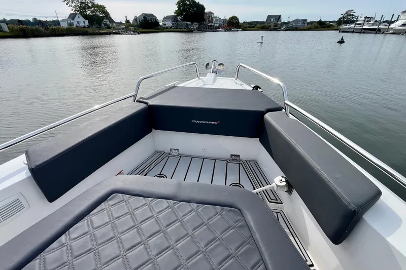 Slide: The Image of 2018 Axopar 37 Sport Cabin R boat interior with cushioned seating on calm water. - 7