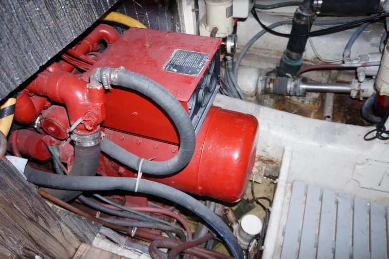 Slide: The Image of Engine compartment of 1988 Ocean Yachts Super Sport, featuring red machinery and hoses. - 18