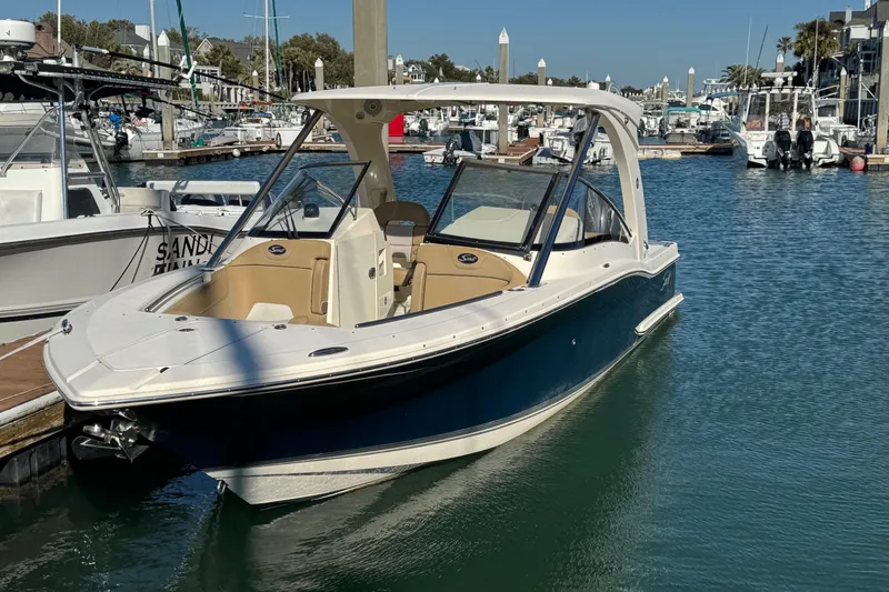 Slide: The Image of 2015 Scout 275 Dorado boat docked in a marina, surrounded by calm water. - 2