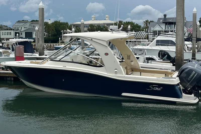Slide: The Image of 2015 Scout 275 Dorado boat docked in a marina, featuring spacious seating and twin engines. - 8