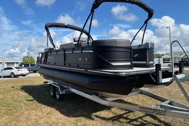 Slide: The Image of 2026 Starcraft SLS 3 R pontoon boat on trailer, parked outdoors under blue sky. - 2