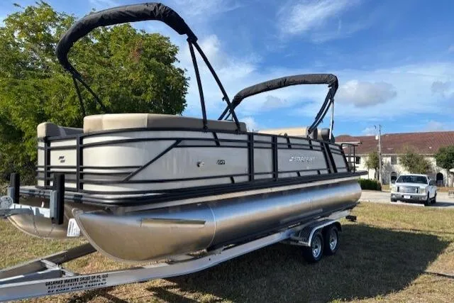 Slide: The Image of 2026 Starcraft EXS 3 DL pontoon boat on trailer, parked on grass under blue sky. - 4