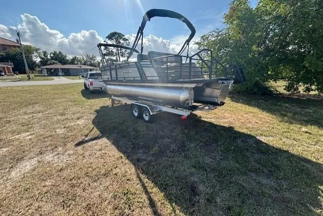 Slide: The Image of 2026 Starcraft EXS 3 DL pontoon boat on trailer, parked on grassy area. - 6