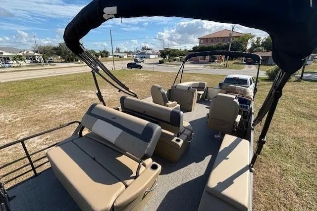 Slide: The Image of 2026 Starcraft EXS 3 DL pontoon boat with beige seating and canopy, parked on grass. - 9