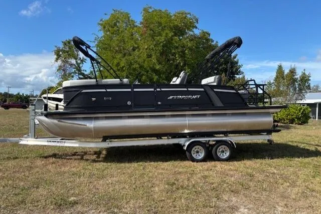 The Image of 2026 Starcraft EXS 3 Q DH pontoon boat on trailer, parked on grass. - 0