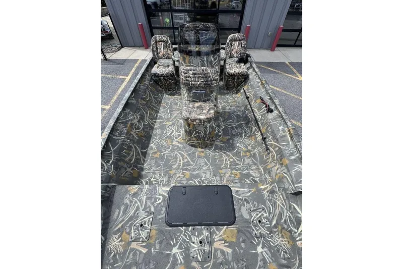 Slide: The Image of 2026 War Eagle 961 Blackhawk boat with camouflage interior and seating, parked outdoors. - 10