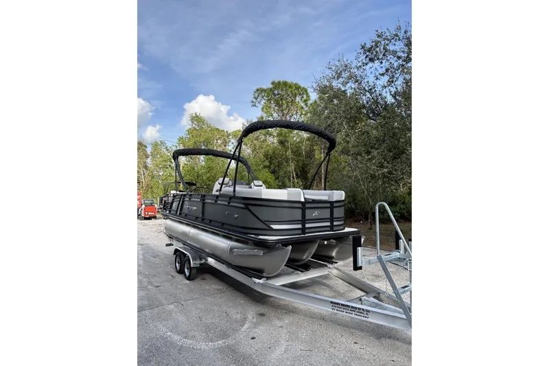 Slide: The Image of 2026 Starcraft EXS 1 Q DH pontoon boat on trailer, parked outdoors. - 2