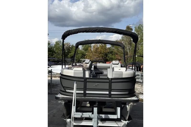 Slide: The Image of 2026 Starcraft EXS 1 Q DH pontoon boat with canopy, parked outdoors under cloudy sky. - 3