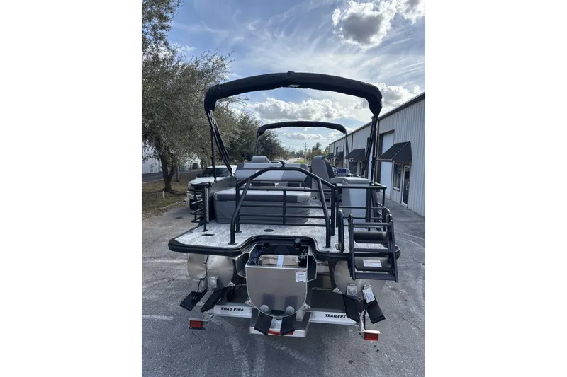 Slide: The Image of 2026 Starcraft EXS 1 Q DH pontoon boat parked outdoors under a cloudy sky. - 7