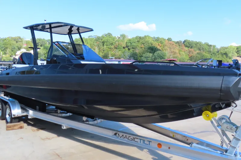 Slide: The Image of 2026 Iron 767 boat on trailer, sleek black design, outdoors with trees in background. - 9