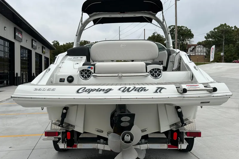 Slide: The Image of 2023 Crownline 290 CR boat, rear view, parked on concrete, showcasing sleek design and propeller. - 2