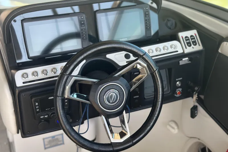 Slide: The Image of 2023 Crownline 290 CR boat dashboard with steering wheel and navigation screens. - 22