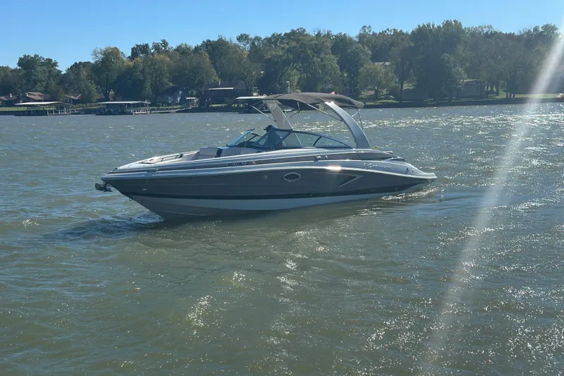 Slide: The Image of 2023 Crownline 290 CR boat cruising on a sunny lake with trees in the background. - 33