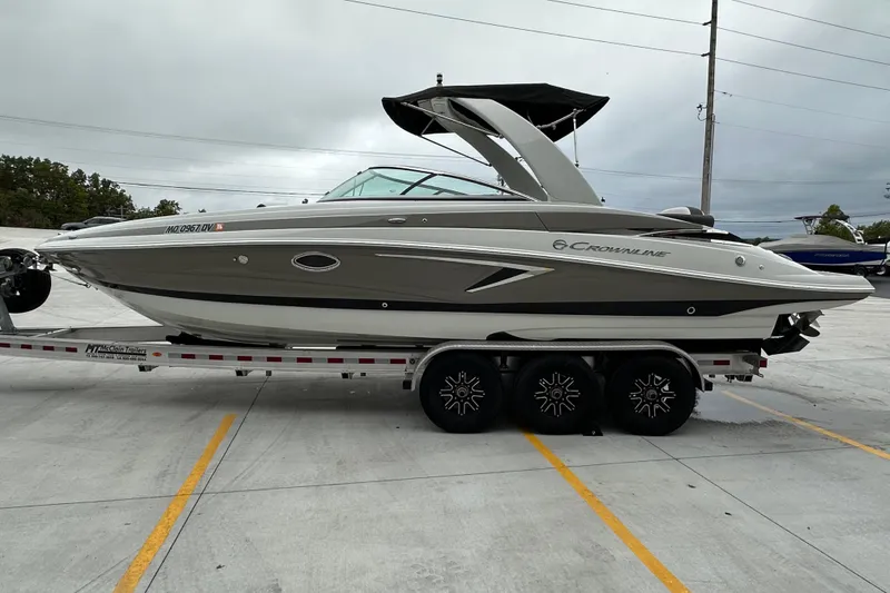 Slide: The Image of 2023 Crownline 290 CR boat on trailer, parked in a lot under cloudy skies. - 4