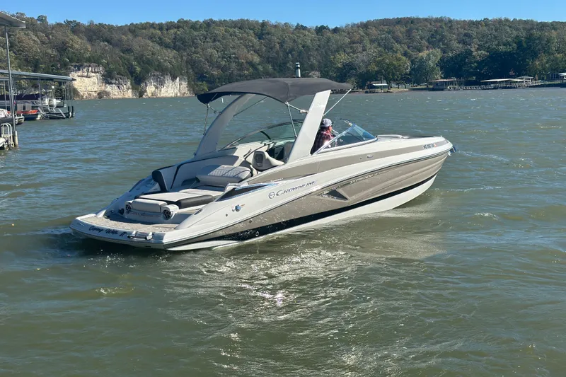Slide: The Image of 2023 Crownline 290 CR boat cruising on a scenic lake with forested hills. - 40