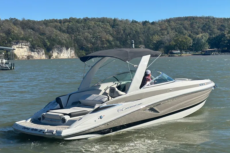 Slide: The Image of 2023 Crownline 290 CR boat cruising on a scenic lake with forested hills. - 46