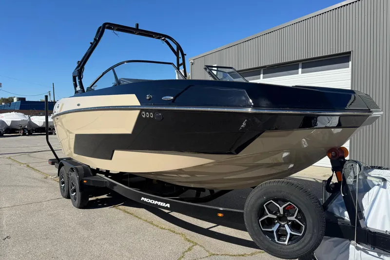 Slide: The Image of 2025 Moomba Max boat on trailer, parked outside a warehouse. - 2