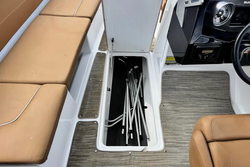 Slide: The Image of 2021 Glastron 205 boat interior with open storage compartment and beige seating. - 19