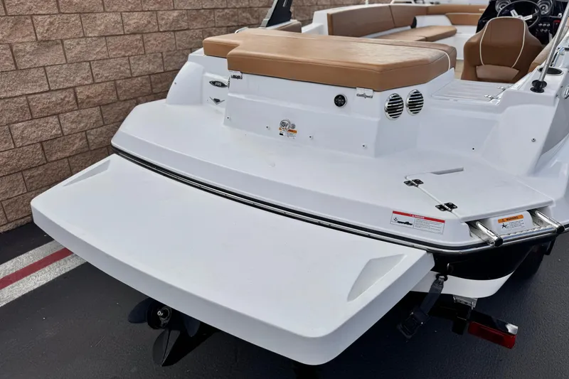 Slide: The Image of 2021 Glastron 205 boat with white deck and tan seating, parked near a brick wall. - 6