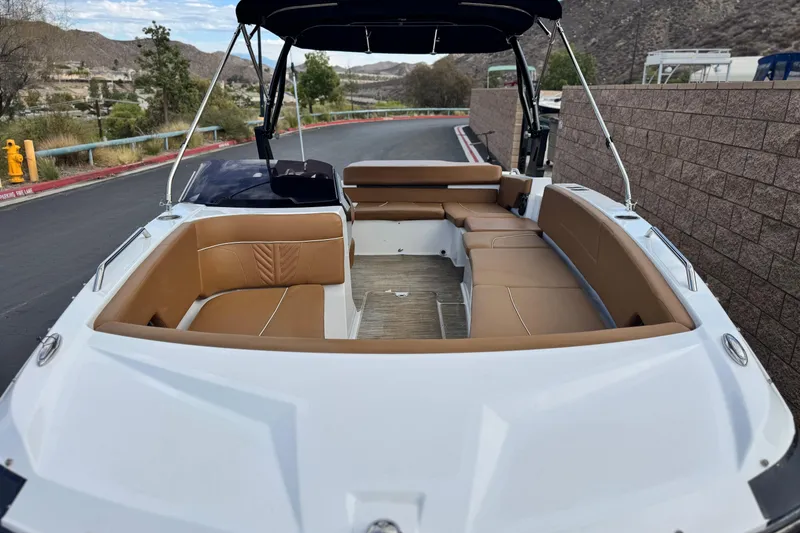 Slide: The Image of 2021 Glastron 205 boat interior with tan seating, parked near a brick wall. - 10