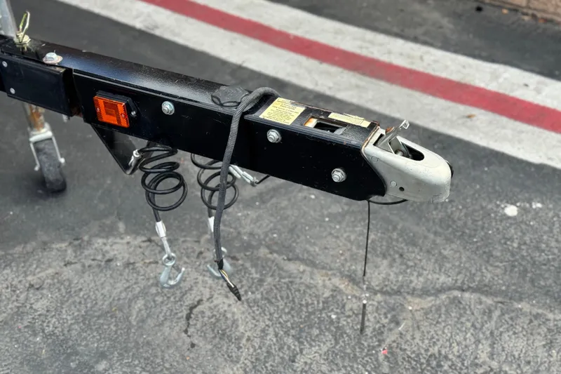 Slide: The Image of Trailer hitch of a 2021 Glastron 205 boat on asphalt pavement. - 24