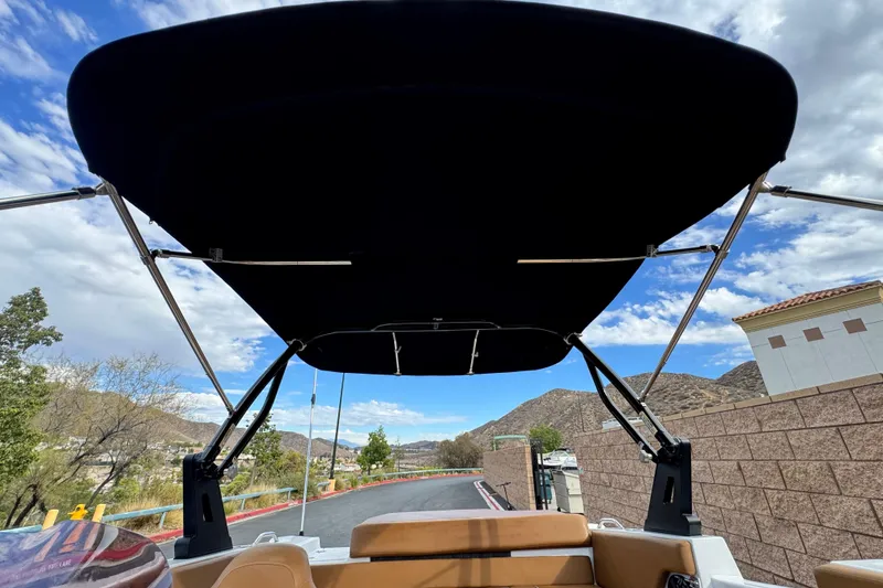 Slide: The Image of 2021 Glastron 205 boat with bimini top, scenic mountain backdrop. - 9