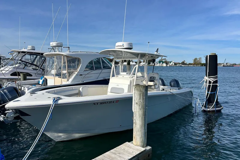 The Image of 2018 Cobia 227 boat docked in marina, clear blue sky, calm water. - 0