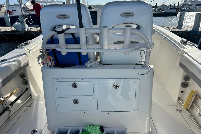 Slide: The Image of 2018 Cobia 227 boat interior with rod holders and storage compartments at a marina. - 5