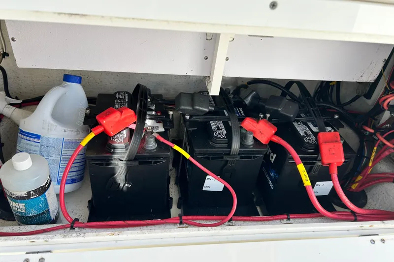 Slide: The Image of 2018 Cobia 227 boat battery compartment with three batteries and cleaning supplies. - 8