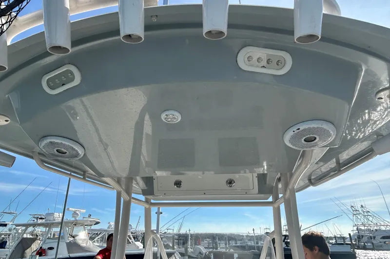 Slide: The Image of 2018 Cobia 227 boat T-top with rod holders and speakers at marina. - 9