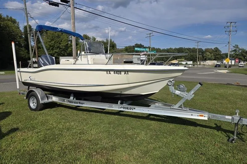The Image of 2000 Scout 185 Sportfish boat on trailer, parked on grass near road. - 1