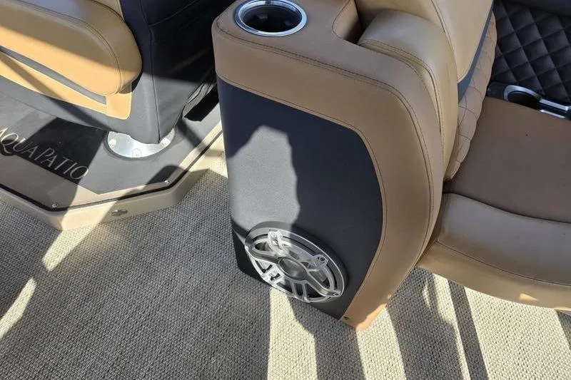 Slide: The Image of 2023 Godfrey AquaPatio 255 SBW boat interior with tan seating and speaker detail. - 21