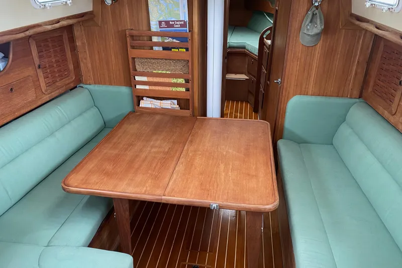 Slide: The Image of 1984 Sabre MK 1 yacht interior with wooden table, green seating, and cozy cabin layout. - 9