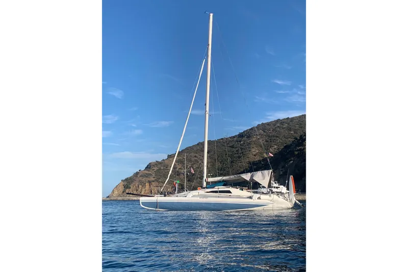 Slide: The Image of Sailboat Corsair 31 UC 2001 on calm water near rocky coastline. - 2
