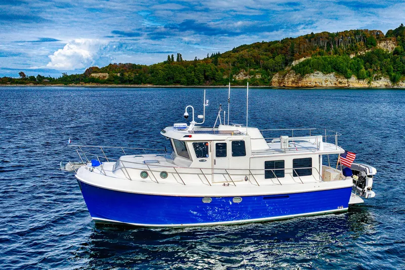 The Image of 2007 American Tug 41 cruising on a scenic lake with lush green shoreline. - 0