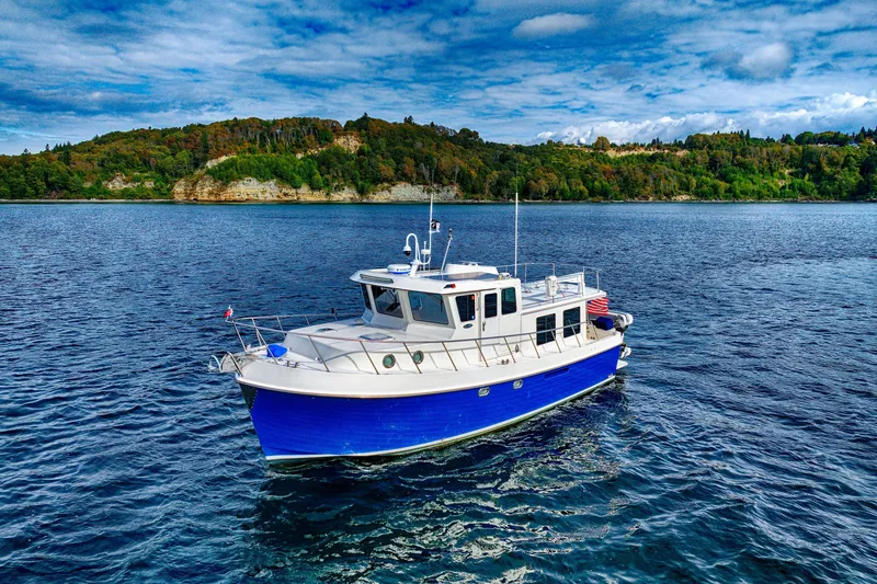 Slide: The Image of 2007 American Tug 41 cruising on a scenic lake with lush green hills. - 2
