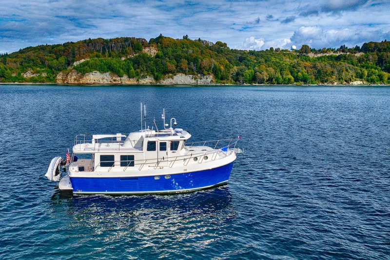 Slide: The Image of 2007 American Tug 41 cruising on a scenic lake with lush green hills in the background. - 3