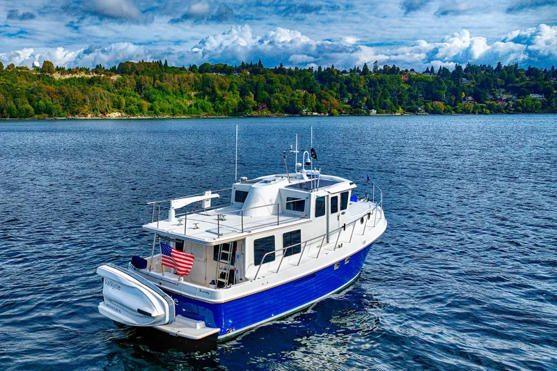 Slide: The Image of American Tug 41, 2007 model, cruising on a scenic lake with lush green shoreline. - 4