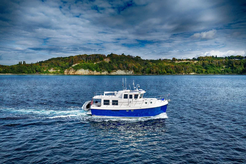 Slide: The Image of 2007 American Tug 41 cruising on a scenic lake with lush green hills. - 8