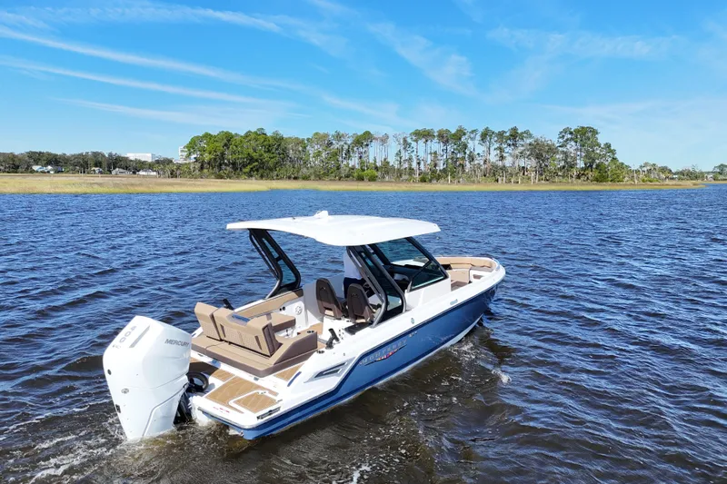 Slide: The Image of 2025 Monterey Elite 27 OB boat cruising on a serene lake under a clear blue sky. - 14